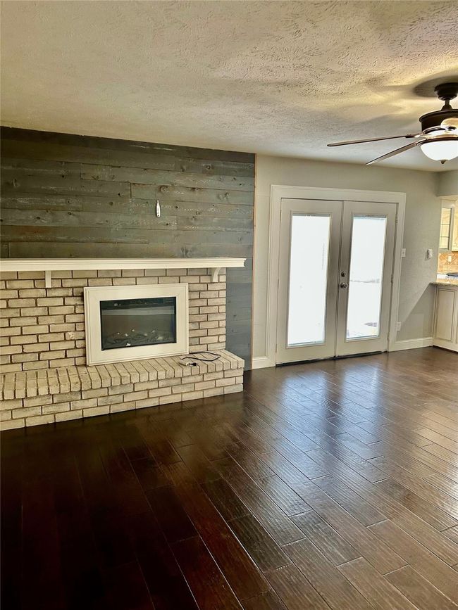 deb with wood finished floors, french doors, a ceiling fan, a textured ceiling, and a fireplace | Image 18