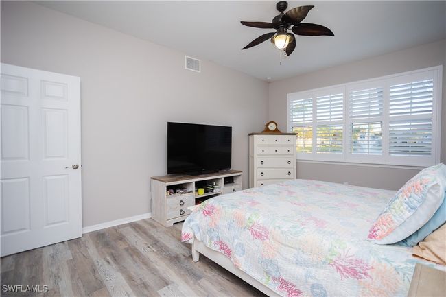 Bedroom with ceiling fan, light wood-style flooring, and baseboards | Image 15