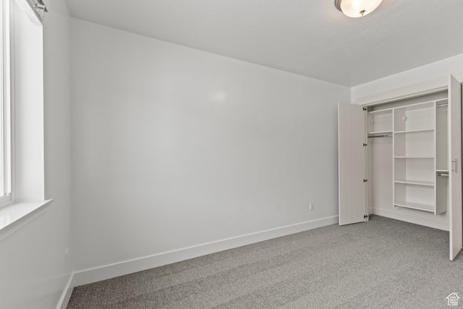 Unfurnished bedroom with a closet, carpet flooring, and baseboards | Image 12