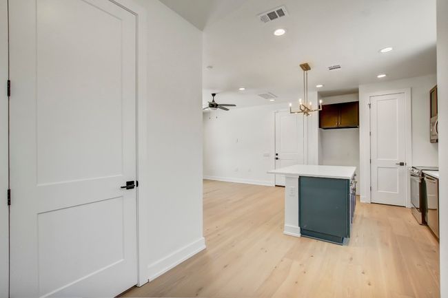 Kitchen featuring baseboards, a center island, light countertops, a ceiling fan, and light wood-type flooring | Image 14