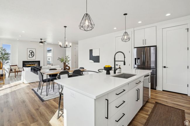 Kitchen with a sink, a glass covered fireplace, pendant lighting, stainless steel appliances, and light wood finished floors | Image 11