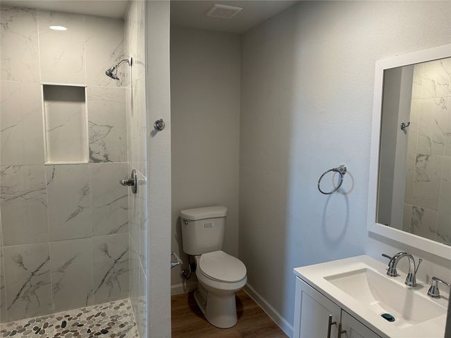 Full bathroom with tiled shower, toilet, visible vents, wood finished floors, and vanity | Image 6