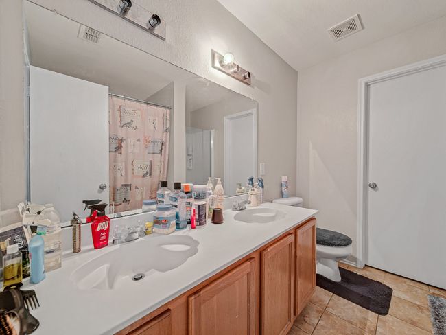 Full bath featuring toilet, double vanity, a shower with curtain, and tile patterned floors | Image 14