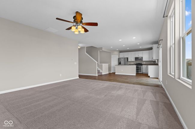 Great room featuring carpet flooring, ceiling fan, recessed lighting, and stairs | Image 7