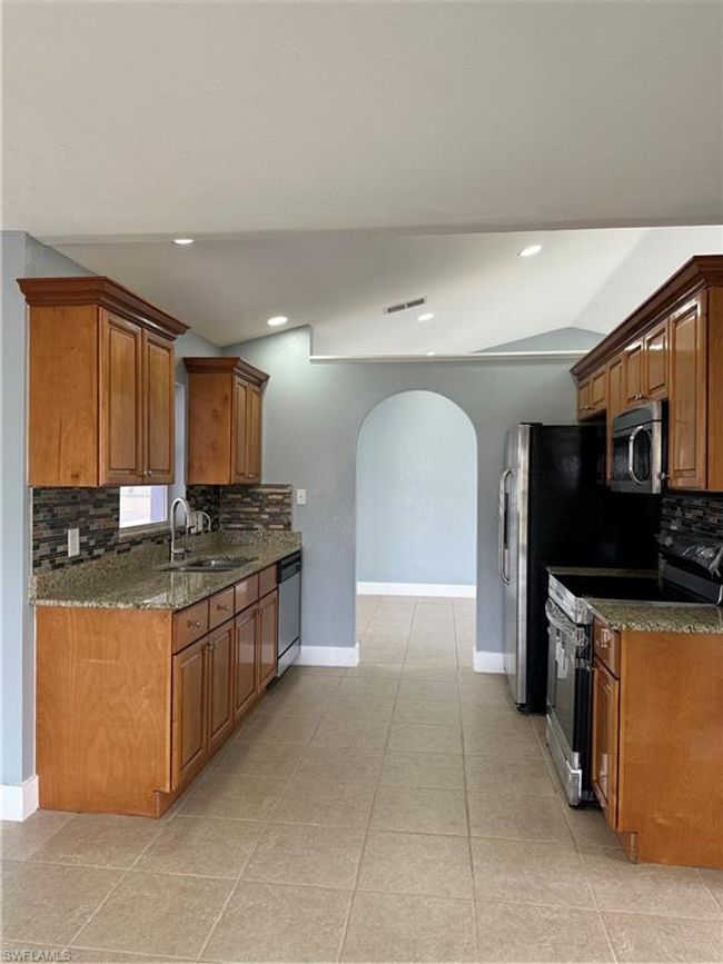 Kitchen featuring range, arched walkways, tasteful backsplash, brown cabinetry, and recessed lighting | Image 13