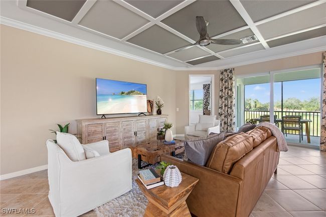 Living room with light tile patterned floors, baseboards, ornamental molding, a ceiling fan, and coffered ceiling | Image 23