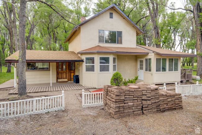 View of front facade with a porch, a shingled roof, stucco siding, and a chimney | Image 4