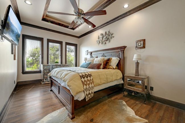Bedroom with baseboards, a raised ceiling, crown molding, recessed lighting, and dark wood-type flooring | Image 33