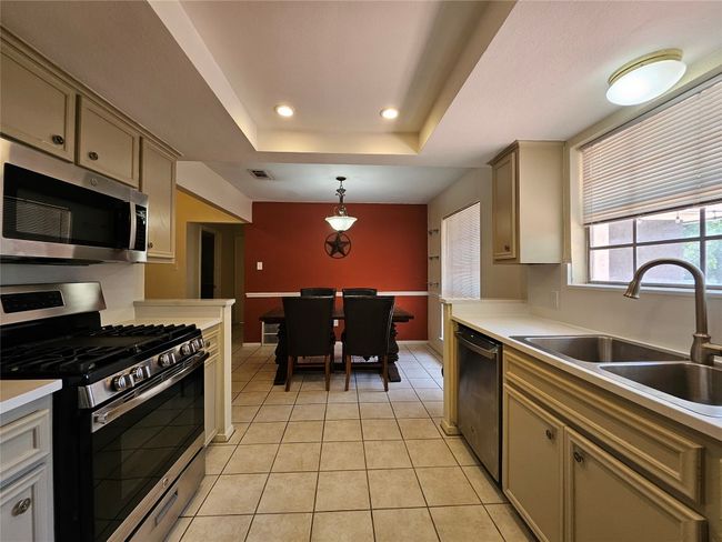 Kitchen with stainless steel appliances, light countertops, a raised ceiling, recessed lighting, and light tile patterned flooring | Image 7