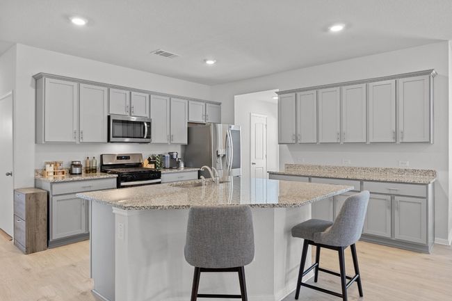 Kitchen featuring a large center island, gray cabinets, deep sink, light wood-look floors, and appliances with stainless steel finishes | Image 7
