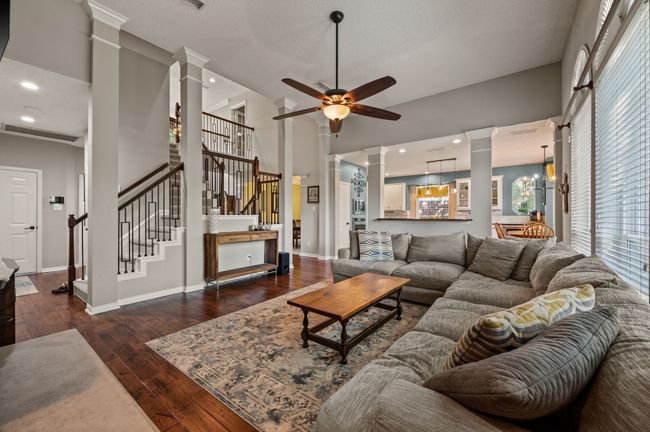 Living area with ornate columns, a ceiling fan, dark wood-style floors, stairway, and a towering ceiling | Image 10