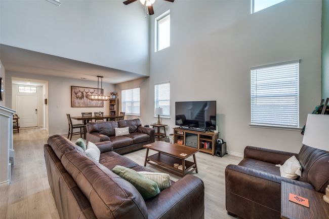 Living room featuring light wood-style floors, a high ceiling, ceiling fan, and a wealth of natural light | Image 6