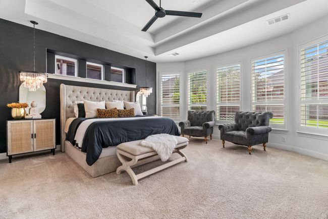 Carpeted bedroom featuring a chandelier, a tray ceiling, and multiple windows | Image 15