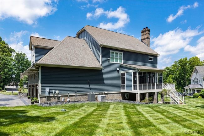 Rear view of property featuring a sunroom, stairway, a chimney, a yard, and a shingled roof | Image 47