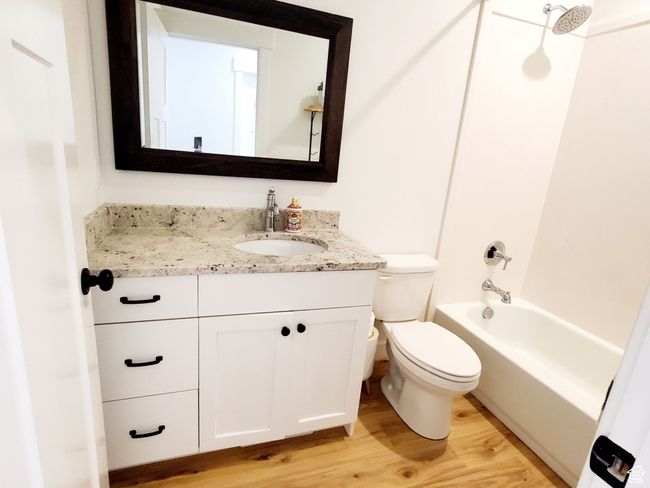 Full bathroom with toilet, washtub / shower combination, wood finished floors, and vanity | Image 13
