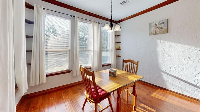 Dining space featuring a textured wall, visible vents, crown molding, baseboards, and hardwood / wood-style flooring | Image 16