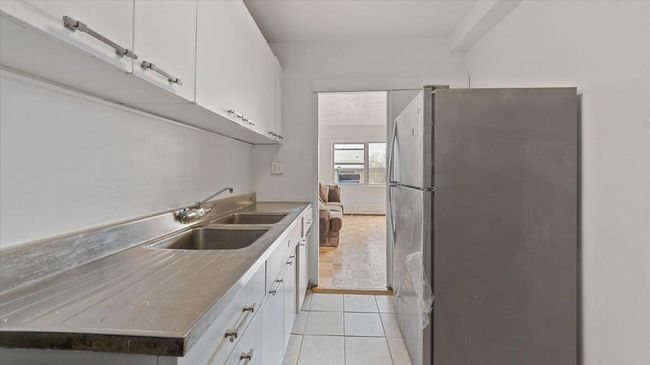 Kitchen featuring a sink, light tile patterned floors, freestanding refrigerator, and white cabinetry | Image 12