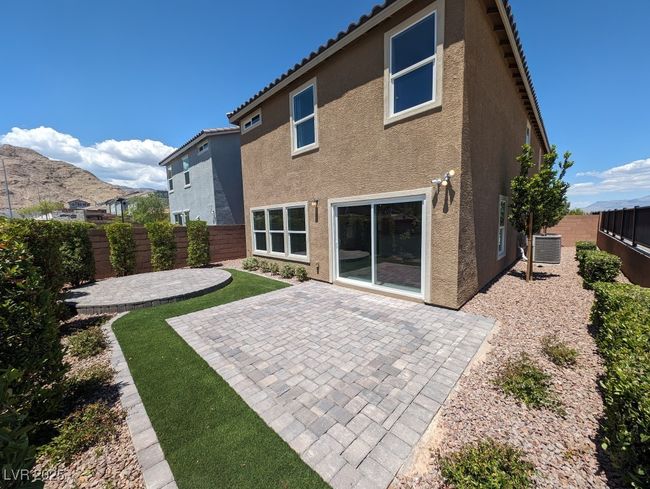 Back of property with stucco siding, a patio area, a fenced backyard, and a tiled roof | Image 13