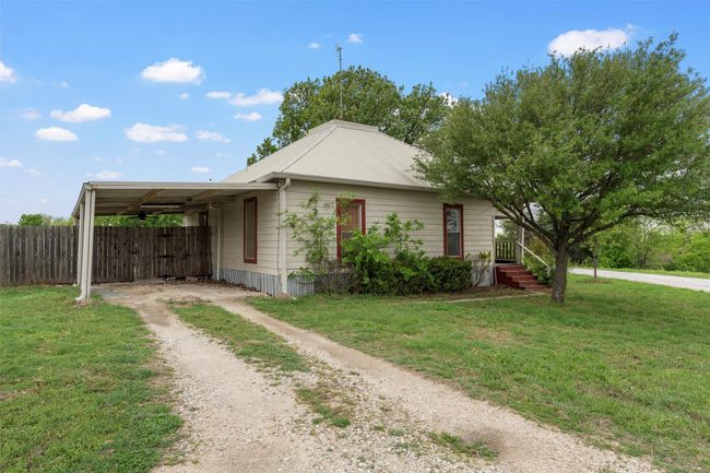 View of home's exterior with driveway, an attached carport, fence, metal roof, and a lawn | Image 19