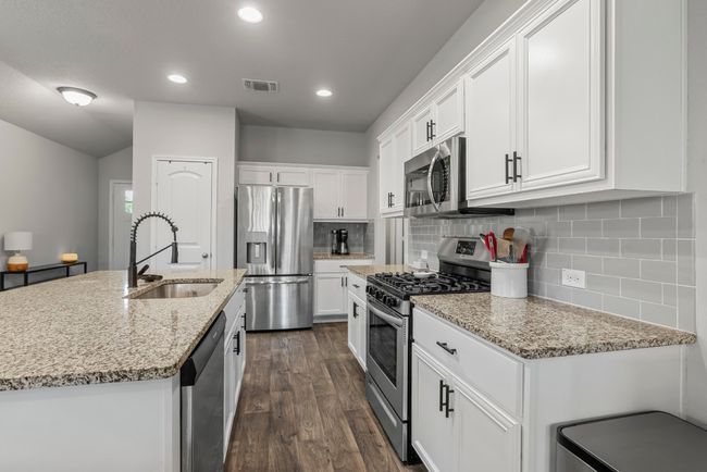 Kitchen with stainless steel appliances, dark wood-style flooring, white cabinets, decorative backsplash, and recessed lighting | Image 11