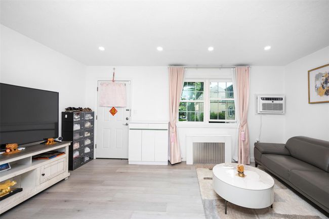 Living room with light wood-style flooring, recessed lighting, radiator, and a wall unit AC | Image 13