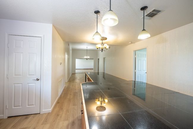 Corridor featuring visible vents, baseboards, a chandelier, light wood-style floors, and a textured ceiling | Image 10