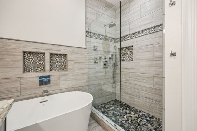 Bathroom featuring a stand alone soaking tub, a shower stall, and tile walls | Image 19