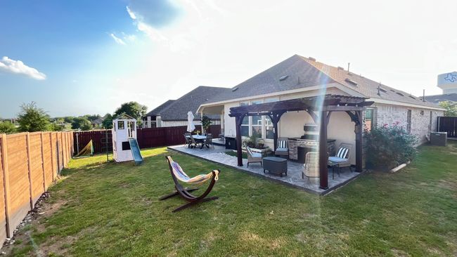 Rear view of property featuring a pergola, a playground, a patio, outdoor lounge area, and an outdoor kitchen | Image 31