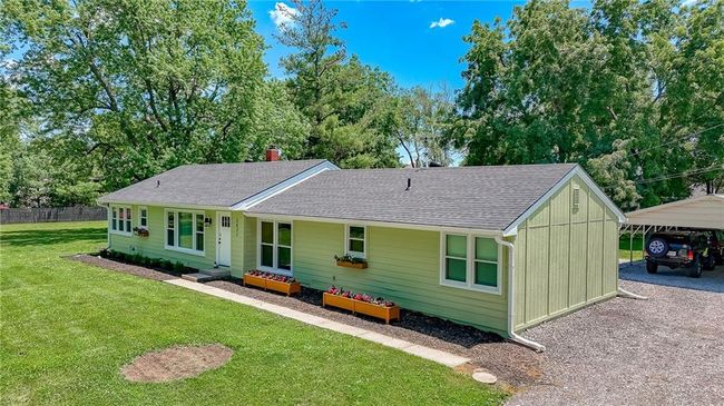 Ranch-style home with a detached carport, a shingled roof, a chimney, and gravel driveway | Image 37