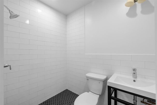 Tasteful, Renovated Bathroom with tiled shower, toilet, and tile walls. | Image 8