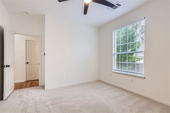 Empty room with a ceiling fan, light carpet, baseboards, and a smoke detector | Image 24