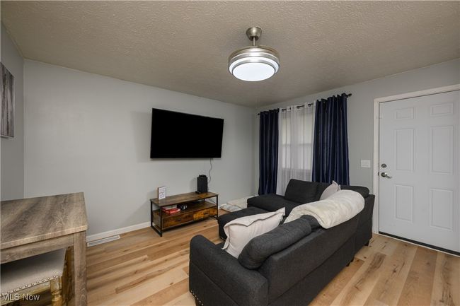 Living room featuring light wood-style flooring and a textured ceiling | Image 4