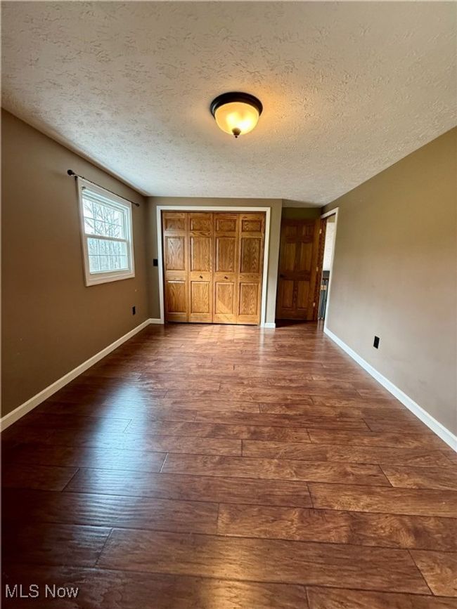 Unfurnished bedroom featuring dark wood-style floors, a textured ceiling, a closet, and baseboards | Image 32