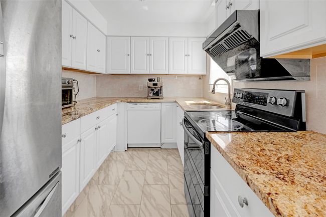 Kitchen featuring electric range, dishwasher, a sink, freestanding refrigerator, and light marble finish flooring | Image 9