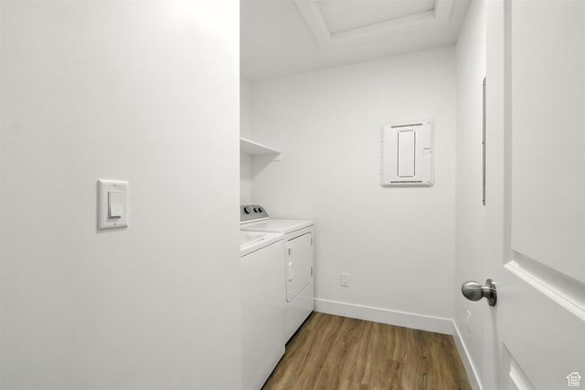 Laundry area with electric panel, independent washer and dryer, light wood finished floors, and attic access | Image 17