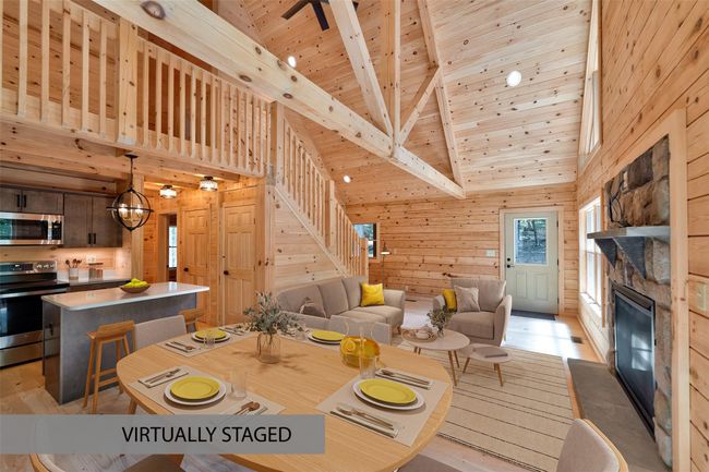 Dining room featuring wooden walls, a wood ceiling with exposed beams, a stone fireplace, light wood finished floors, and high vaulted ceiling | Image 9