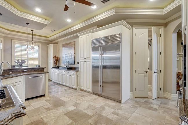 Kitchen with stainless steel appliances, ornamental molding, a sink, a ceiling fan, and a tray ceiling | Image 17