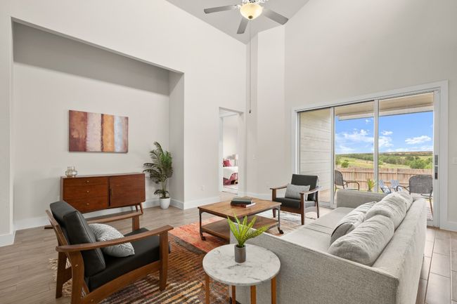 Living area featuring a towering ceiling, a ceiling fan, and light wood-style floors | Image 19