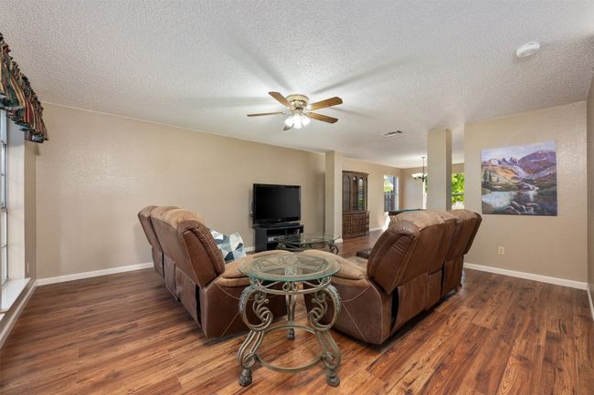 Living area with baseboards, a textured ceiling, visible vents, ceiling fan, and wood finished floors | Image 6