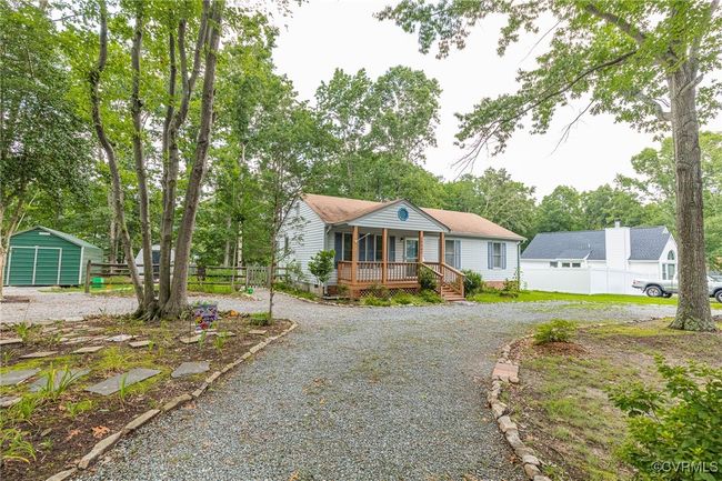 Bungalow-style house with covered porch, driveway, view of scattered trees, and a storage shed | Image 48