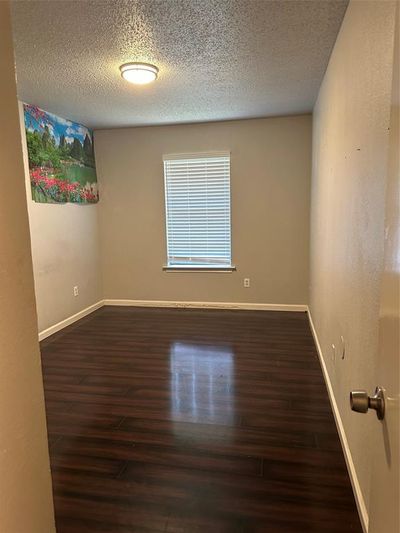 Spare room featuring dark hardwood / wood-style flooring and a textured ceiling | Image 3