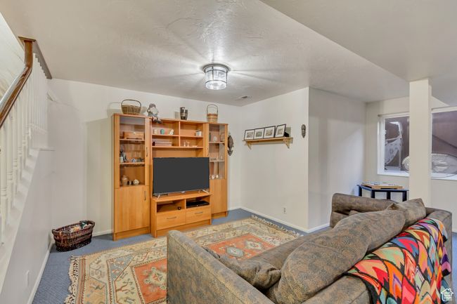 Carpeted living area featuring baseboards, a textured ceiling, and stairway | Image 25
