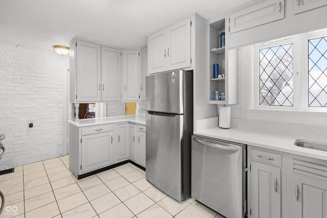 kitchen with light countertops, white cabinetry, appliances with stainless steel finishes, and brick wall | Image 19