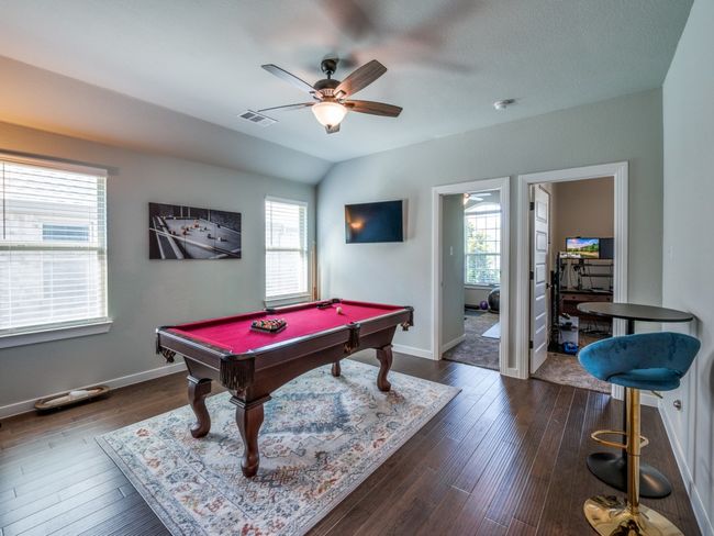 Playroom with dark wood finished floors, visible vents, pool table, baseboards, and ceiling fan | Image 29