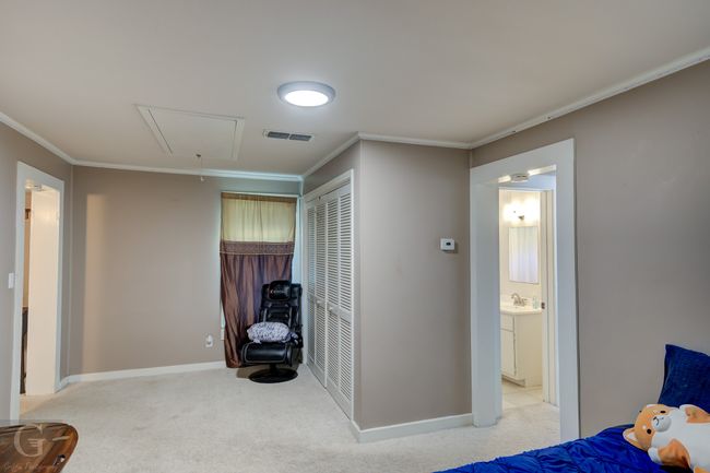 Bedroom with attic access, light carpet, crown molding, baseboards, and a sink | Image 19