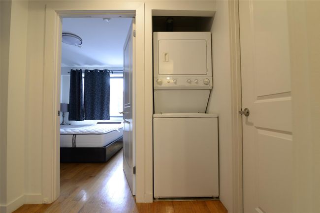 Laundry room featuring stacked washer and clothes dryer and wood finished floors | Image 8