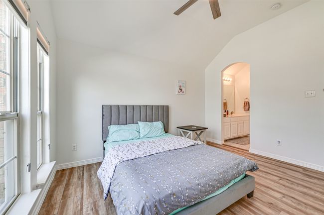 Bedroom featuring light hardwood / wood-style floors, lofted ceiling, multiple windows, and ceiling fan | Image 35