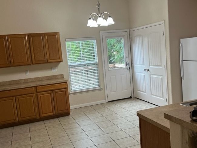 Interior space with plenty of natural light, hanging light fixtures, white fridge, and an inviting chandelier. | Image 7
