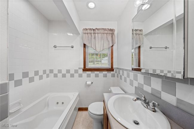 Bathroom with vanity, toilet, a bath, tile walls, and tile patterned flooring | Image 13