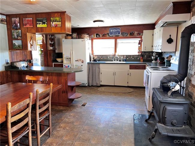 Kitchen featuring white appliances, sink, a wood stove, and white cabinets | Image 19